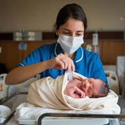 Indian doctors and nurses observing a newborn baby during post-delivery monitoring in a maternity ward