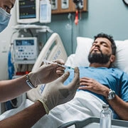 Doctor providing acute illness treatment to adult patient with fever in hospital